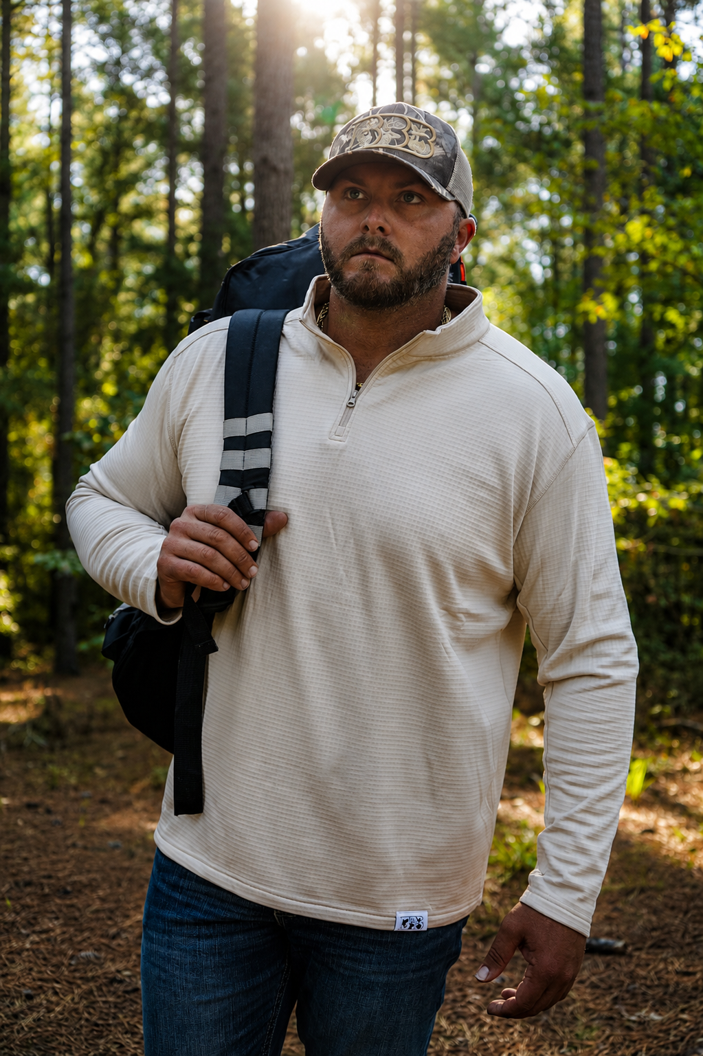Zach Rushing wearing a tan bbb outdoors waffle pullover while walking through the woods.